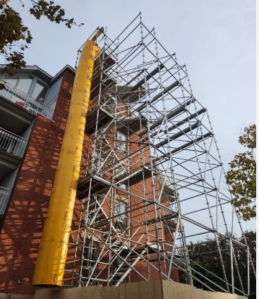 Scaffold stair tower and chute beside a brick building
